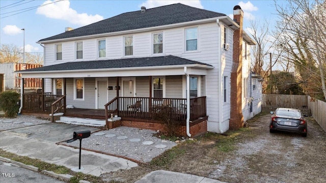 view of front of property featuring covered porch, driveway, a chimney, and roof with shingles