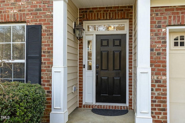 doorway to property with a garage and brick siding