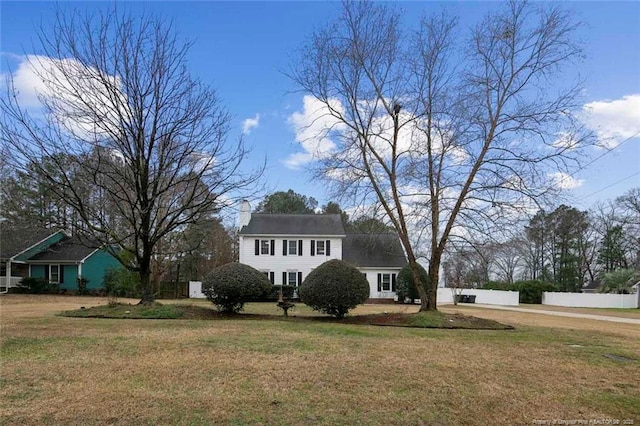 view of front facade featuring a front lawn, fence, and a chimney