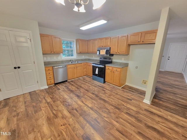 kitchen featuring an inviting chandelier, stainless steel appliances, sink, and hardwood / wood-style floors