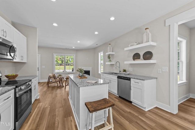 412 N Green St, Selma, NC 27576 - kitchen with stainless steel appliances, open shelves, a sink, a center island, and wood finished floors