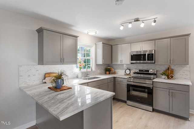 kitchen with gray cabinetry, sink, kitchen peninsula, and appliances with stainless steel finishes