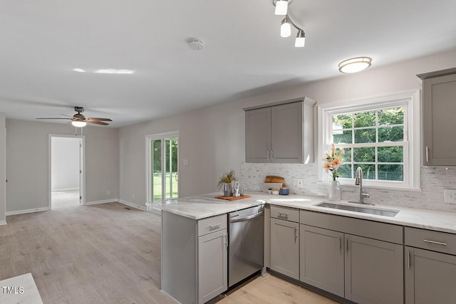 kitchen featuring sink, light hardwood / wood-style flooring, tasteful backsplash, stainless steel dishwasher, and kitchen peninsula