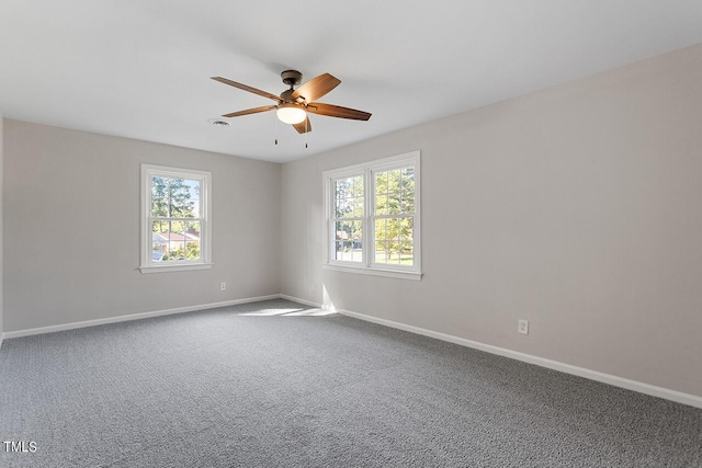 carpeted empty room featuring ceiling fan and a wealth of natural light