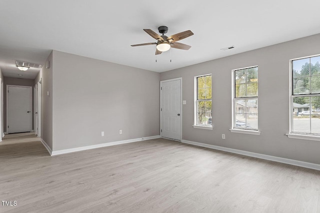 unfurnished room with light wood finished floors, visible vents, and baseboards