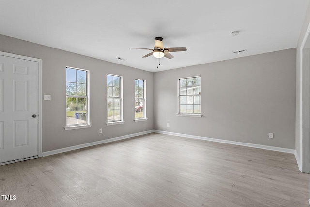 spare room featuring a ceiling fan, light wood-type flooring, visible vents, and baseboards