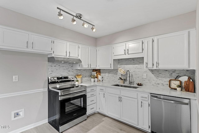 kitchen with under cabinet range hood, a sink, white cabinetry, light countertops, and appliances with stainless steel finishes