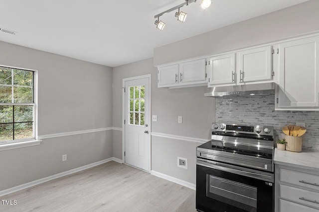 kitchen featuring under cabinet range hood, electric range, visible vents, white cabinets, and decorative backsplash