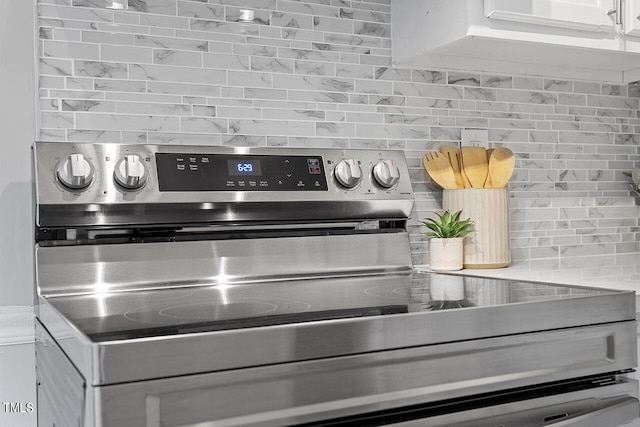 details featuring electric stove, backsplash, and white cabinetry