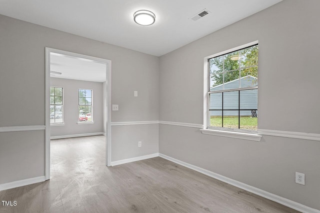 spare room featuring baseboards, visible vents, and wood finished floors