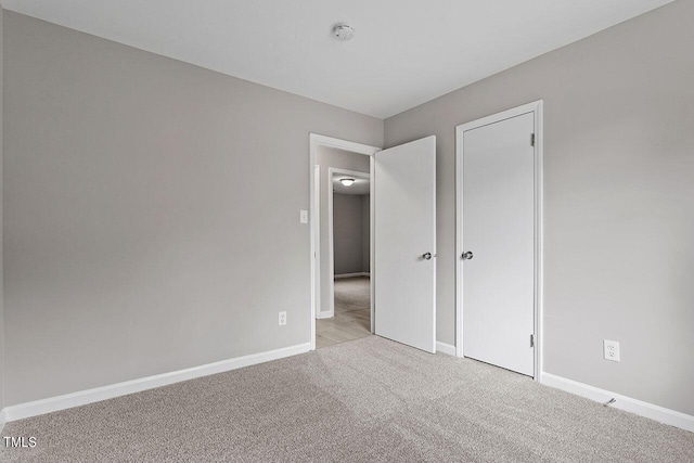 unfurnished bedroom featuring light carpet and baseboards