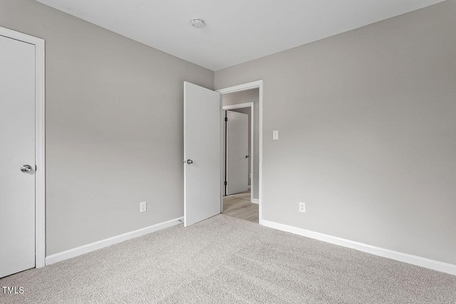 unfurnished room featuring baseboards and light colored carpet