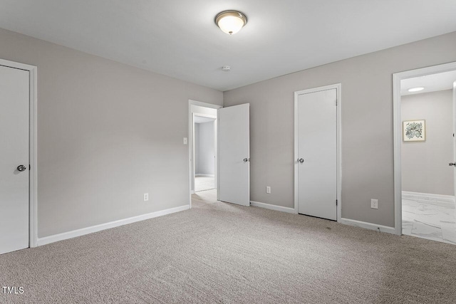 unfurnished bedroom with carpet floors, ensuite bath, and baseboards