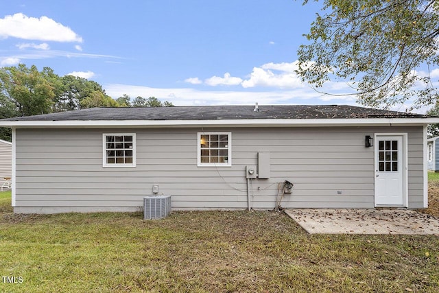 rear view of property featuring a yard and cooling unit