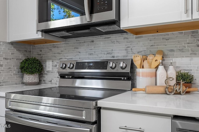 kitchen featuring white cabinetry, light stone counters, decorative backsplash, and appliances with stainless steel finishes