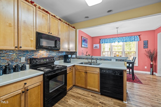 kitchen with sink, light hardwood / wood-style floors, black appliances, hanging light fixtures, and tasteful backsplash