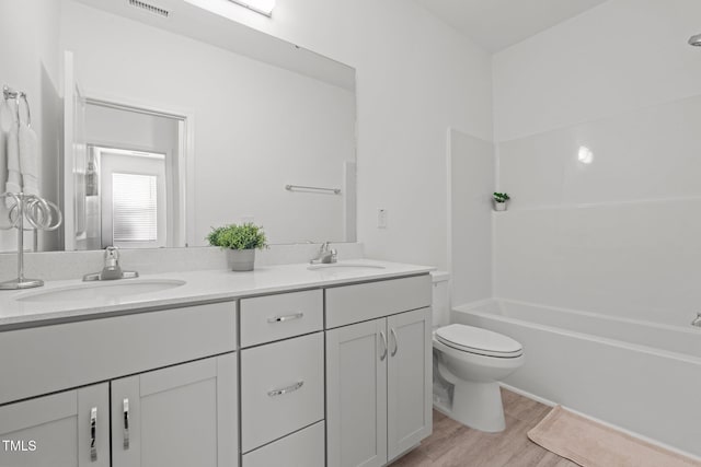 full bathroom featuring double vanity, wood finished floors, a sink, and toilet