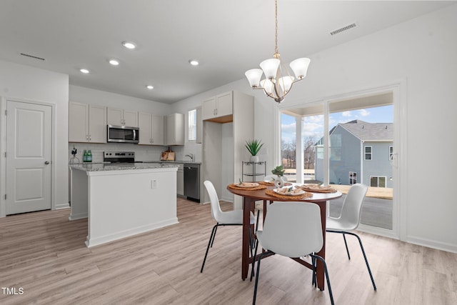 dining room with light wood-style flooring, visible vents, and a healthy amount of sunlight