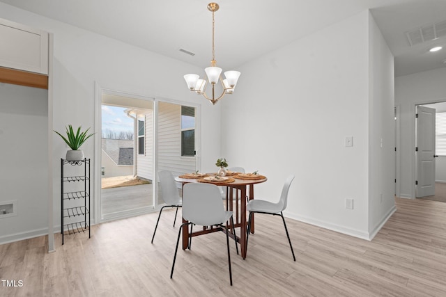 dining room with light wood finished floors, baseboards, visible vents, and an inviting chandelier