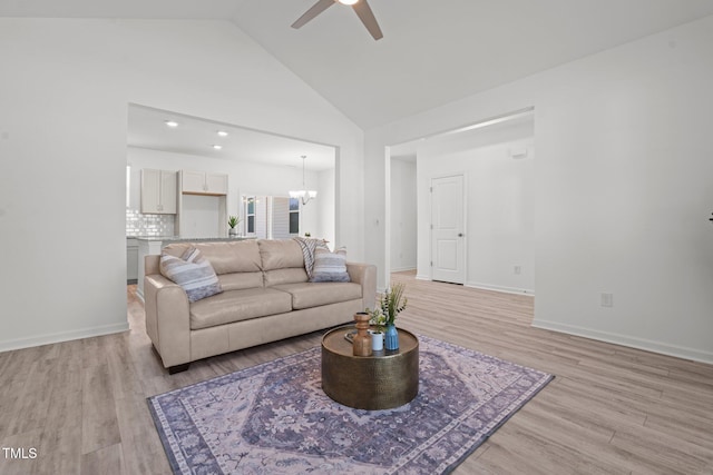 living area featuring light wood-style floors, high vaulted ceiling, baseboards, and ceiling fan with notable chandelier