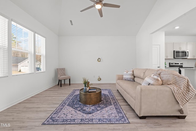 living room featuring visible vents, light wood-style flooring, a ceiling fan, high vaulted ceiling, and baseboards