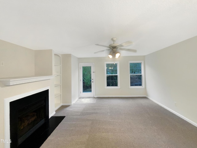 living room featuring ceiling fan, carpet flooring, a fireplace with flush hearth, built in features, and baseboards