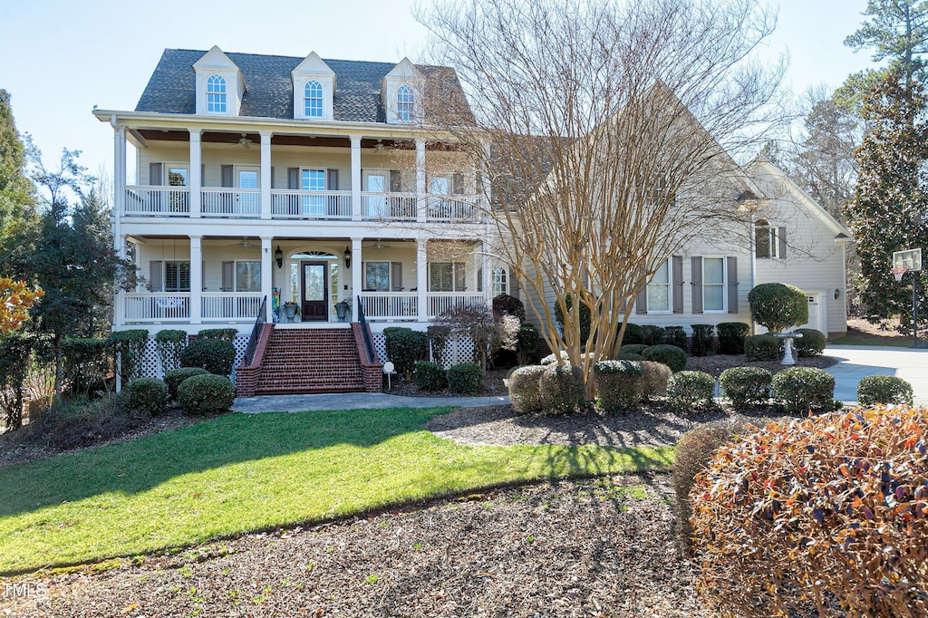 view of front of property featuring a front lawn, a balcony, and a porch