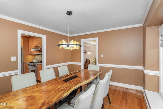 dining space featuring baseboards, a notable chandelier, ornamental molding, and light wood finished floors