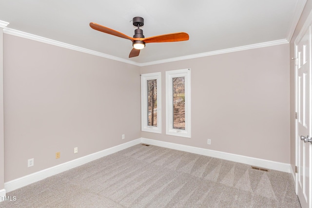 carpeted empty room with visible vents, baseboards, crown molding, and ceiling fan