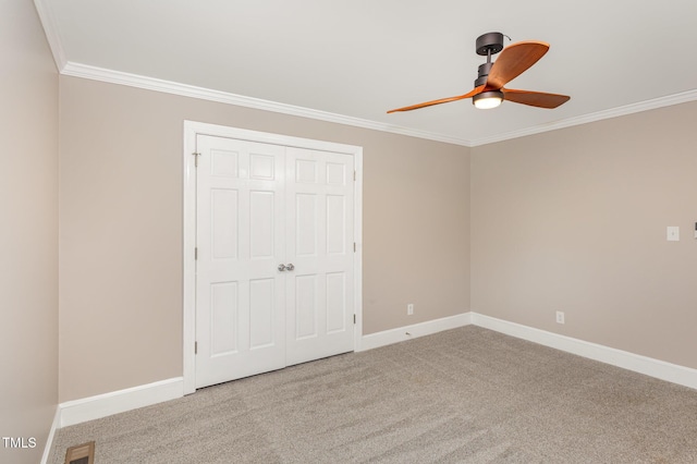 unfurnished bedroom featuring crown molding, carpet flooring, baseboards, and visible vents