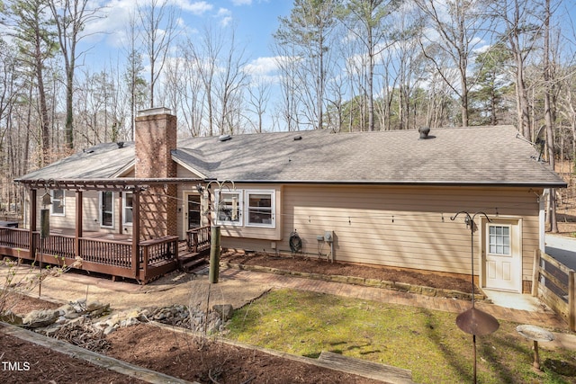 back of house featuring a wooden deck, a chimney, and a shingled roof