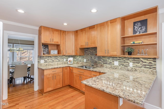 kitchen with open shelves, light stone counters, light wood finished floors, and a sink