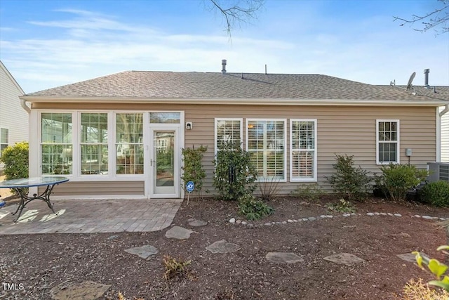 rear view of property featuring a patio area, central AC unit, and a shingled roof