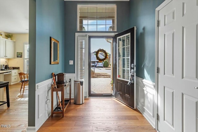 foyer entrance featuring a wainscoted wall and light wood finished floors