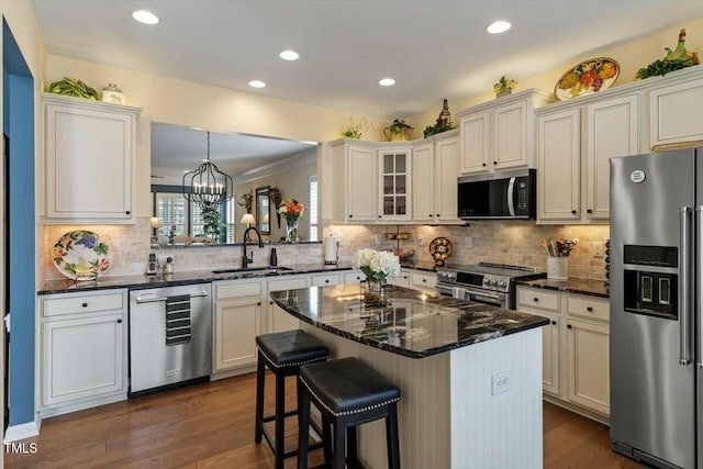 kitchen featuring a sink, a kitchen breakfast bar, a center island, stainless steel appliances, and dark wood-style flooring