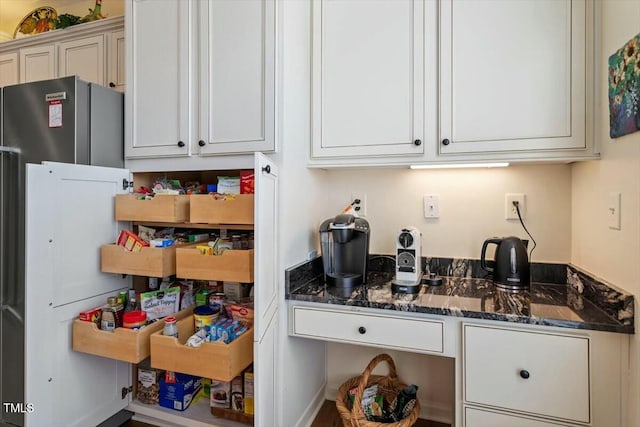 kitchen featuring white cabinetry and dark stone countertops