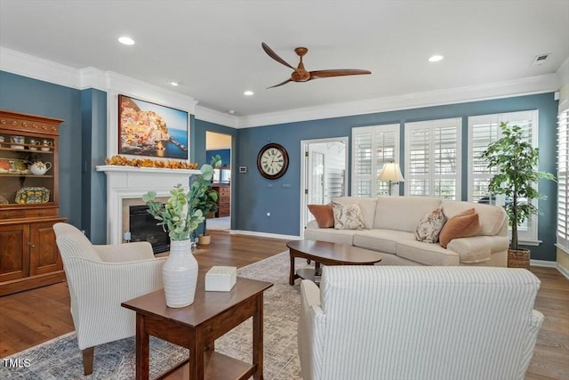 living room featuring a glass covered fireplace, recessed lighting, wood finished floors, and ornamental molding