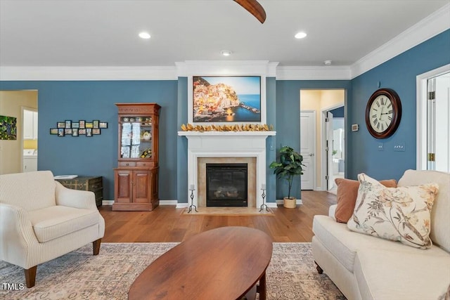 living area featuring wood finished floors, a fireplace with flush hearth, washer / dryer, and ornamental molding