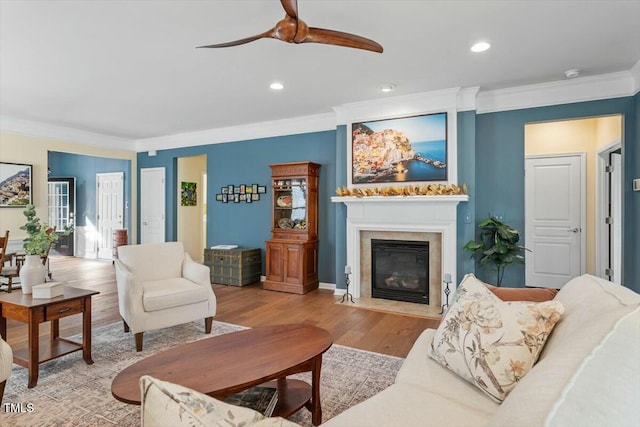 living room featuring a fireplace with flush hearth, ornamental molding, recessed lighting, wood finished floors, and a ceiling fan