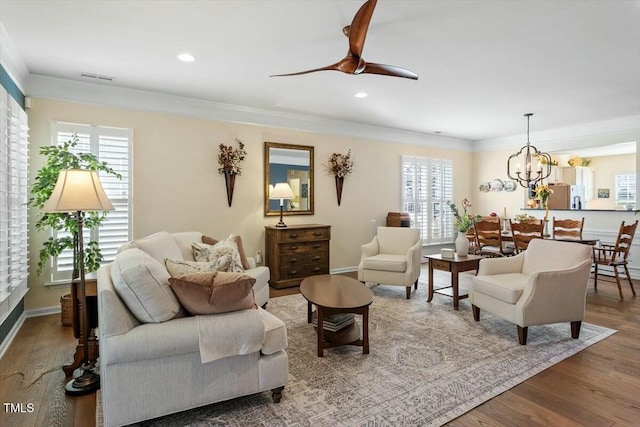 living room with wood finished floors, visible vents, a wealth of natural light, and ornamental molding