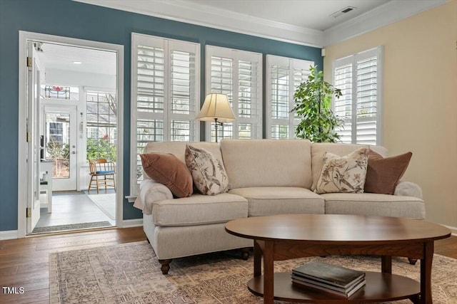 living area featuring crown molding, plenty of natural light, wood finished floors, and visible vents