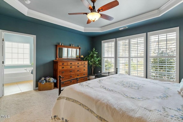 tiled bedroom with visible vents, a tray ceiling, ensuite bath, carpet, and crown molding