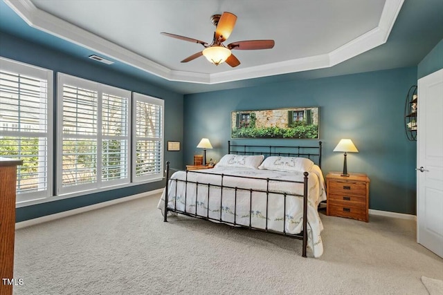 carpeted bedroom with visible vents, ceiling fan, baseboards, a tray ceiling, and ornamental molding