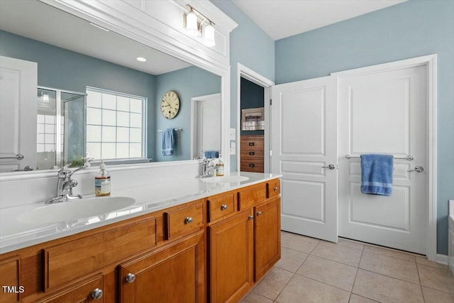 bathroom featuring tile patterned floors, double vanity, a stall shower, and a sink