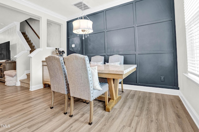 dining space with crown molding and light hardwood / wood-style flooring