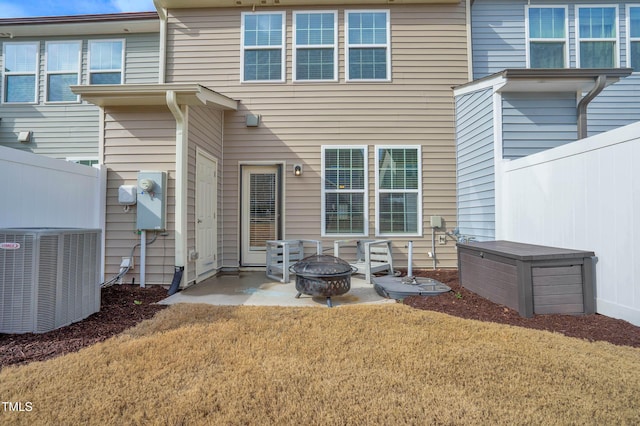 back of house with cooling unit, an outdoor fire pit, a patio area, and a lawn