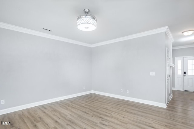 spare room with visible vents, crown molding, baseboards, and wood finished floors