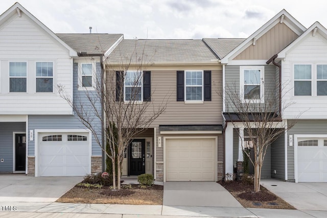 townhome / multi-family property with a garage, concrete driveway, board and batten siding, and stone siding