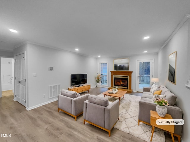 living room with crown molding and light wood-type flooring