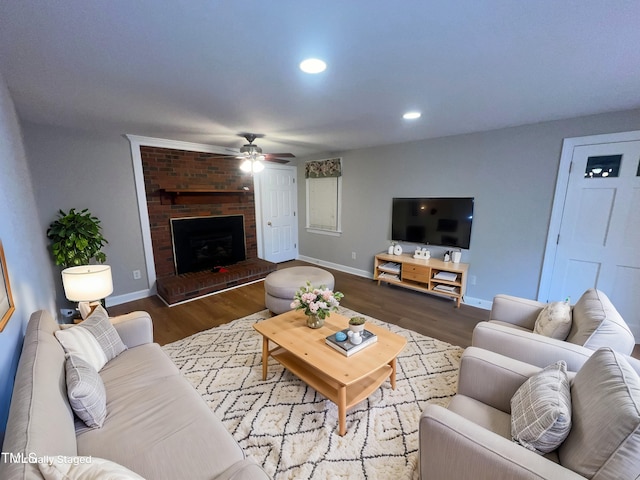 living room featuring a brick fireplace, dark hardwood / wood-style floors, and ceiling fan